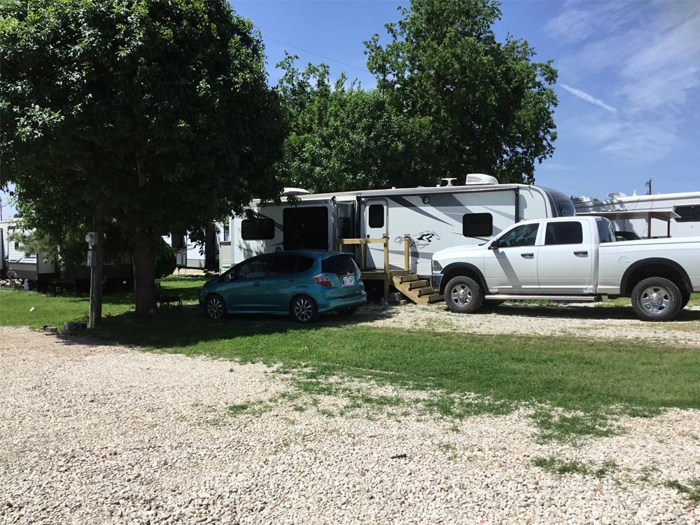 A car and truck parked next to a trailer at BROKEN SPOKE RV