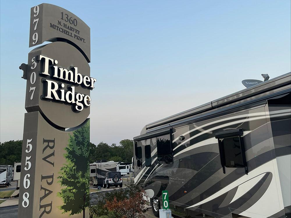 A motorhome parked next to the park sign at TIMBER RIDGE RV PARK