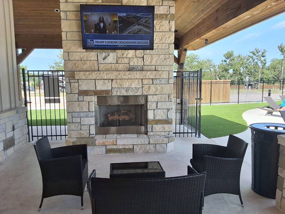 Covered outdoor fireplace with seating and TV