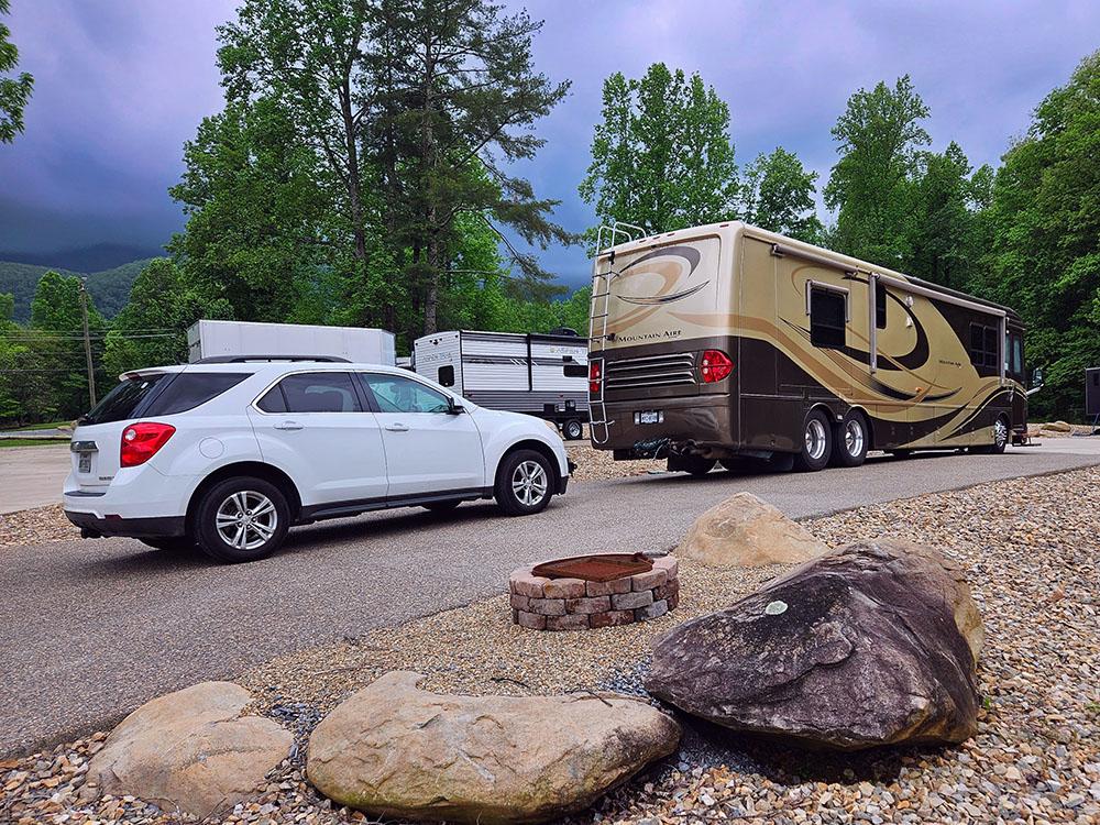 A car and Motorhome parked in a paved site at SMOKY MOUNTAIN PREMIUM CAMPING