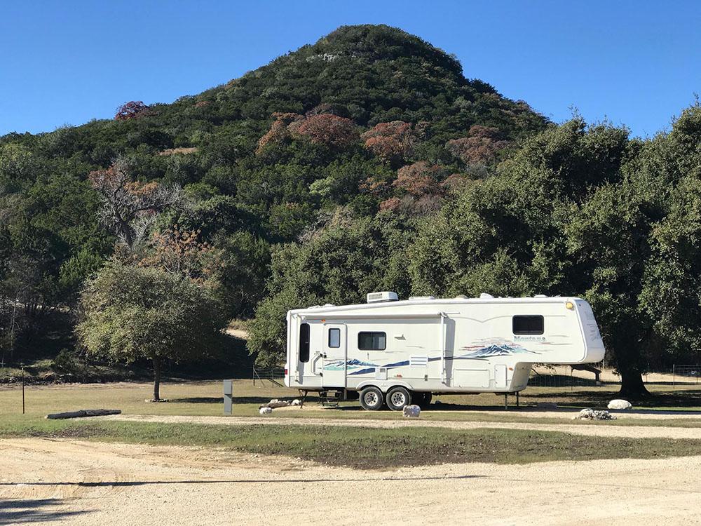 Fifth-wheel trailer with green hill in the background at LOST MAPLES RV AND CAMPING