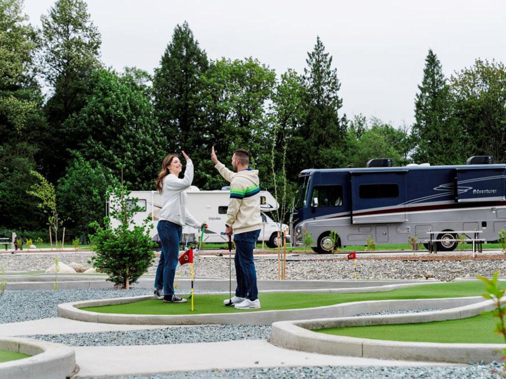 A couple high-fiving on the mini golf course at ANGEL OF THE WINDS CASINO RESORT