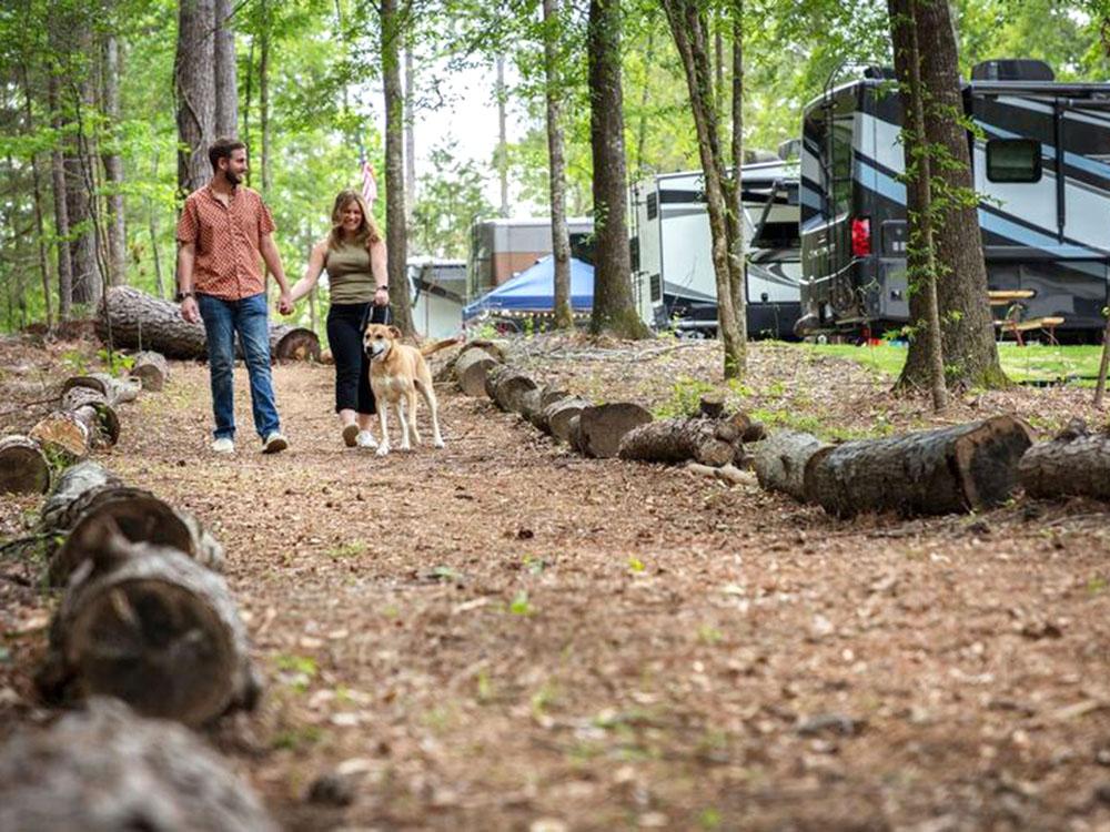 Couple and their dog walking the nature trail at WOODLAND CREEK RV PARK