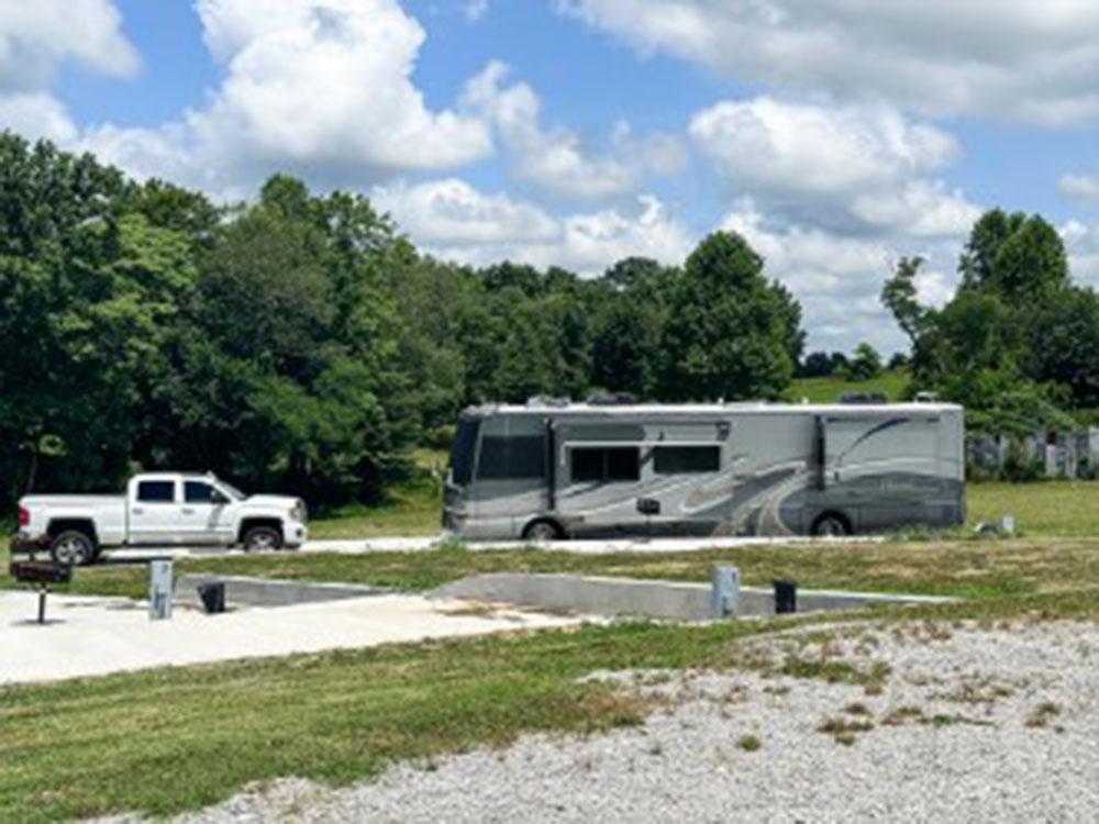 Large RV with a truck in a site at FRANK'S AT CANE HOLLOW RV PARK