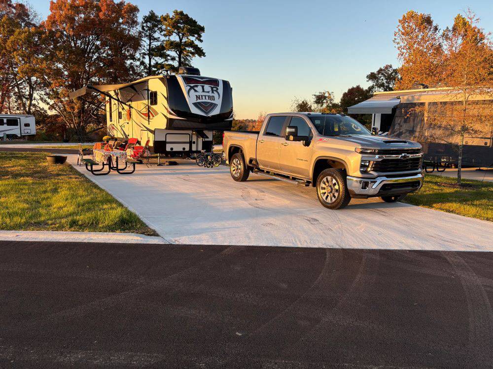 A pickup truck and trailer in a paved site at The Farm RV Resort