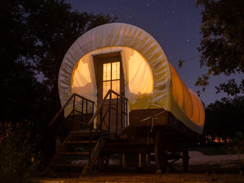 Covered wagon glamping at night at RIVER'S EDGE CAMPGROUND