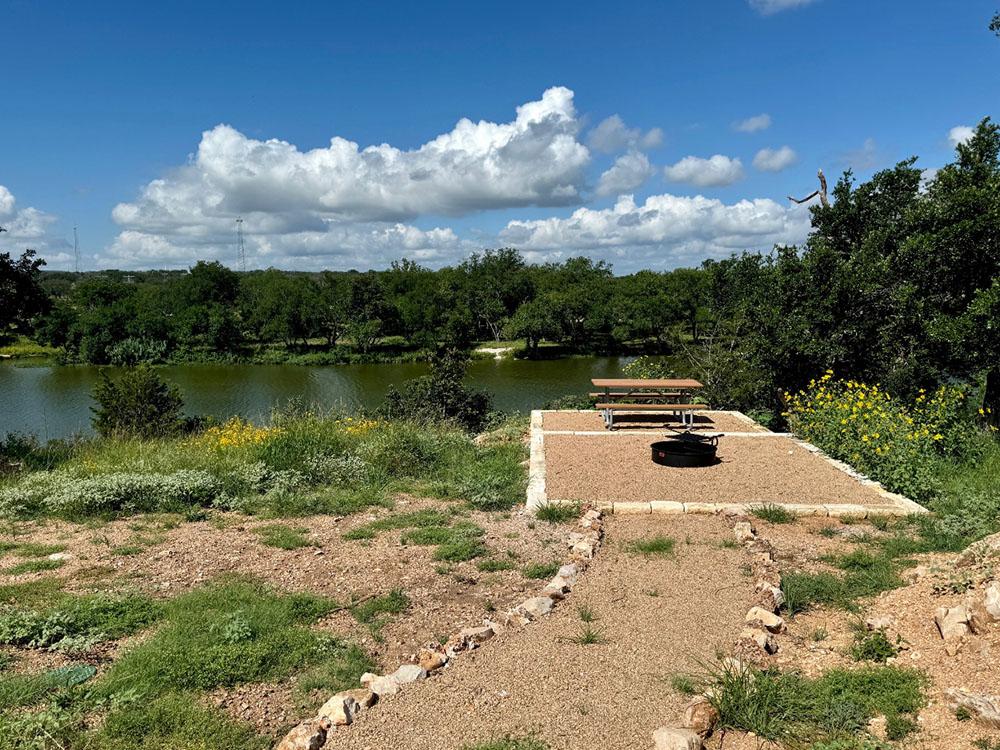 A picnic table and grill on a river's edge patio at RIVER'S EDGE CAMPGROUND