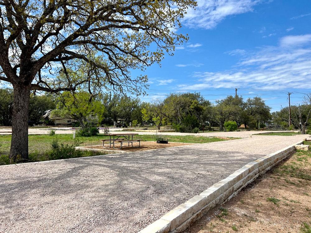 A gravel pull-thru site, picnic table and grill at RIVER'S EDGE CAMPGROUND