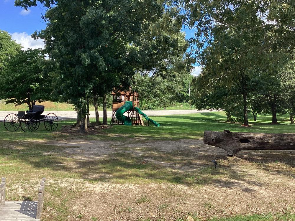 Playground shaded by trees at JESSIE JAMES JUNCTION RV PARK