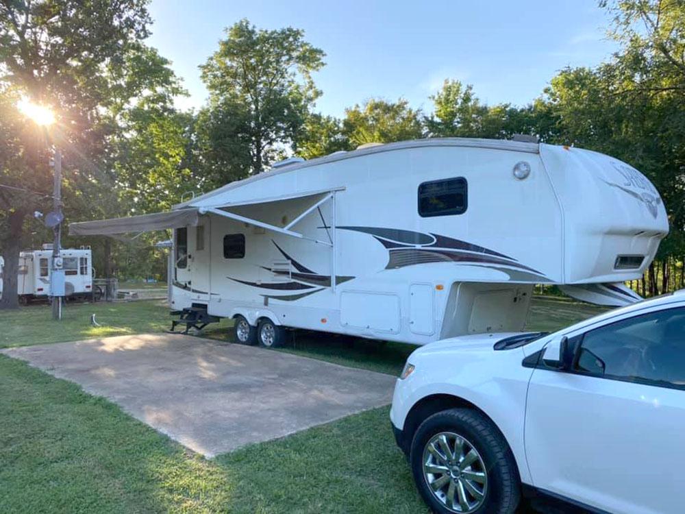 A fifth-wheel with an awning by a patio at PINE RIDGE RV PARK