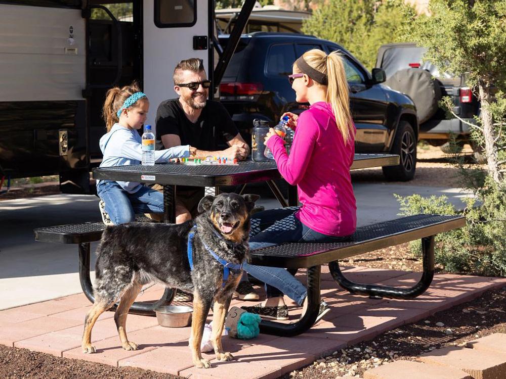 Family sitting at a picnic bench in front of RV at BEST FRIENDS RV PARK