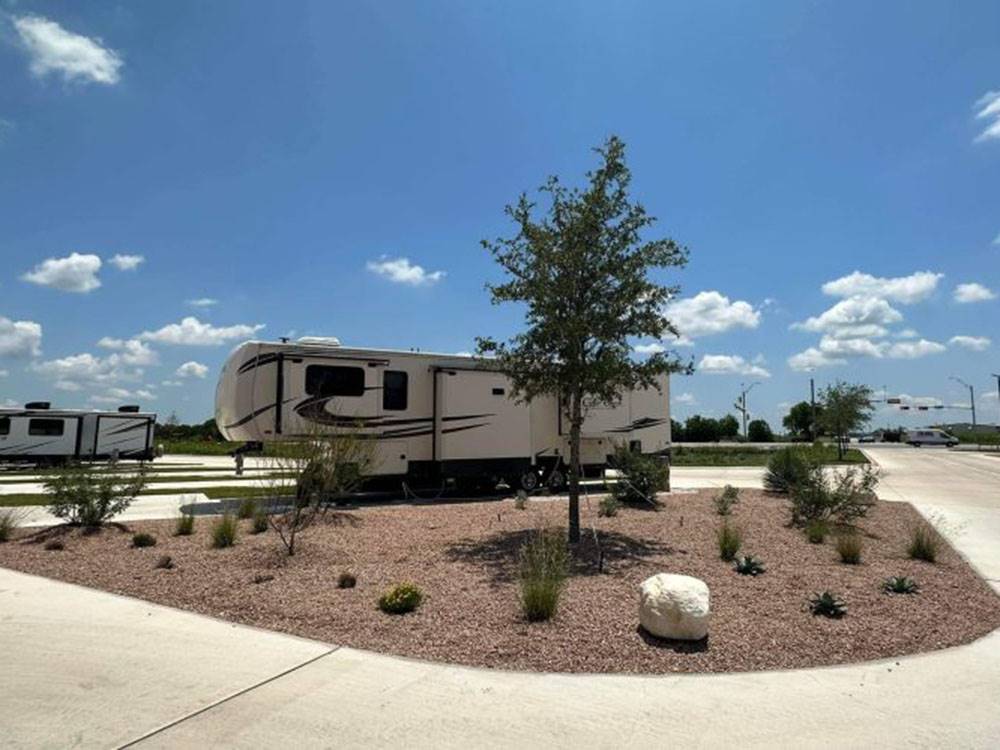 RV parked on lot near trees and gravel