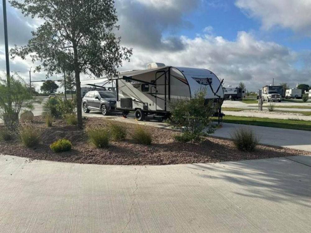 RV parked with car on lot with cloudy sky