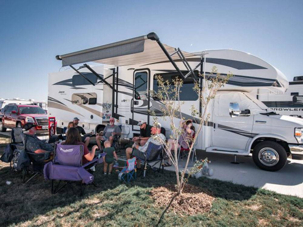 RV parked with a group of people sitting outside in a circle