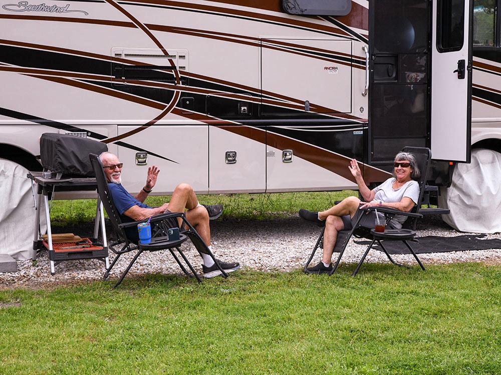 A couple lounging beside their rig at OUR FRIENDS CAMPGROUND