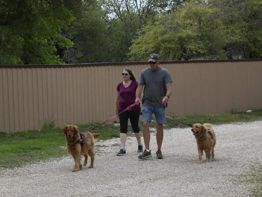 A couple on a walk with their two dogs at OUR FRIENDS CAMPGROUND