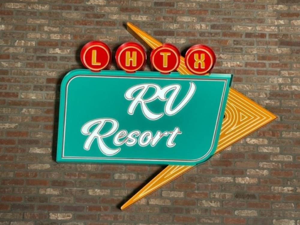 The park sign on the office exterior at LHTX RV Resort