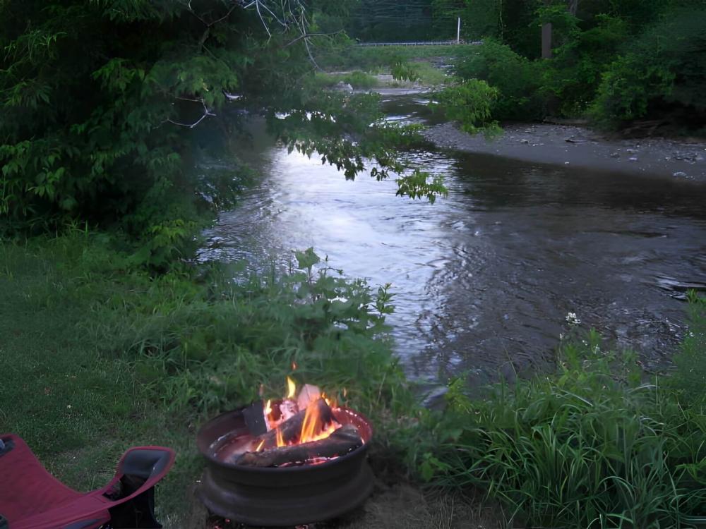 Fire pit in front of creek at site Onion River Campground