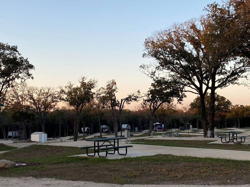 Paved RV sites with tables at dusk at The Woods RV and Cabin Resort