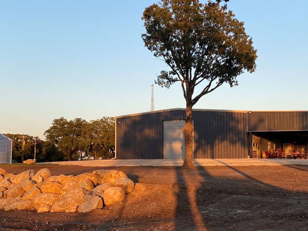 A building, tree and rocks at sunrise at The Woods RV and Cabin Resort