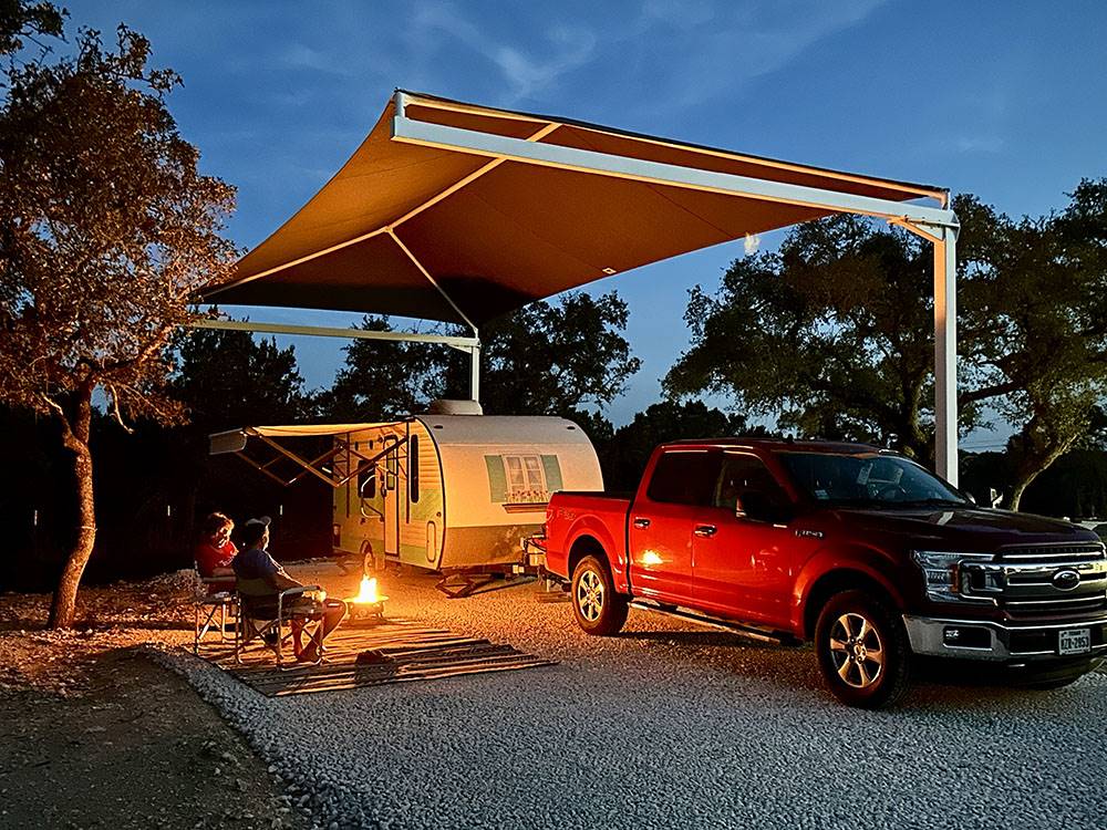 A couple by a fire pit at their covered site