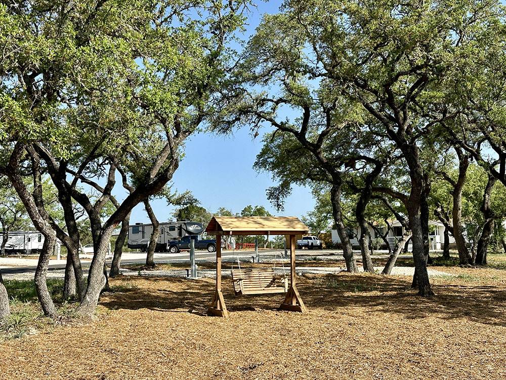 A wooden bench swing between trees