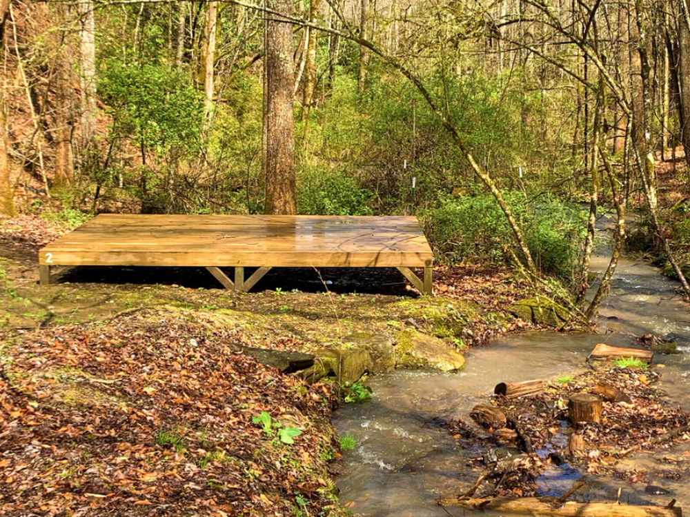 A wood tent platform near the creek at Gorgeous Stays