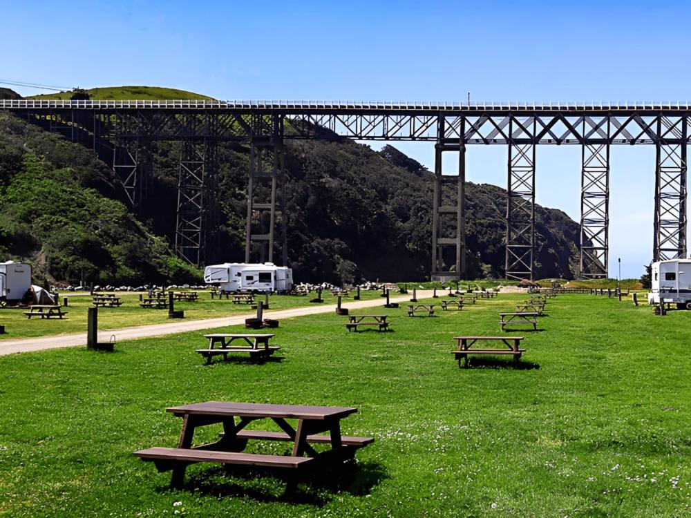 Grassy campsites with bridge in background