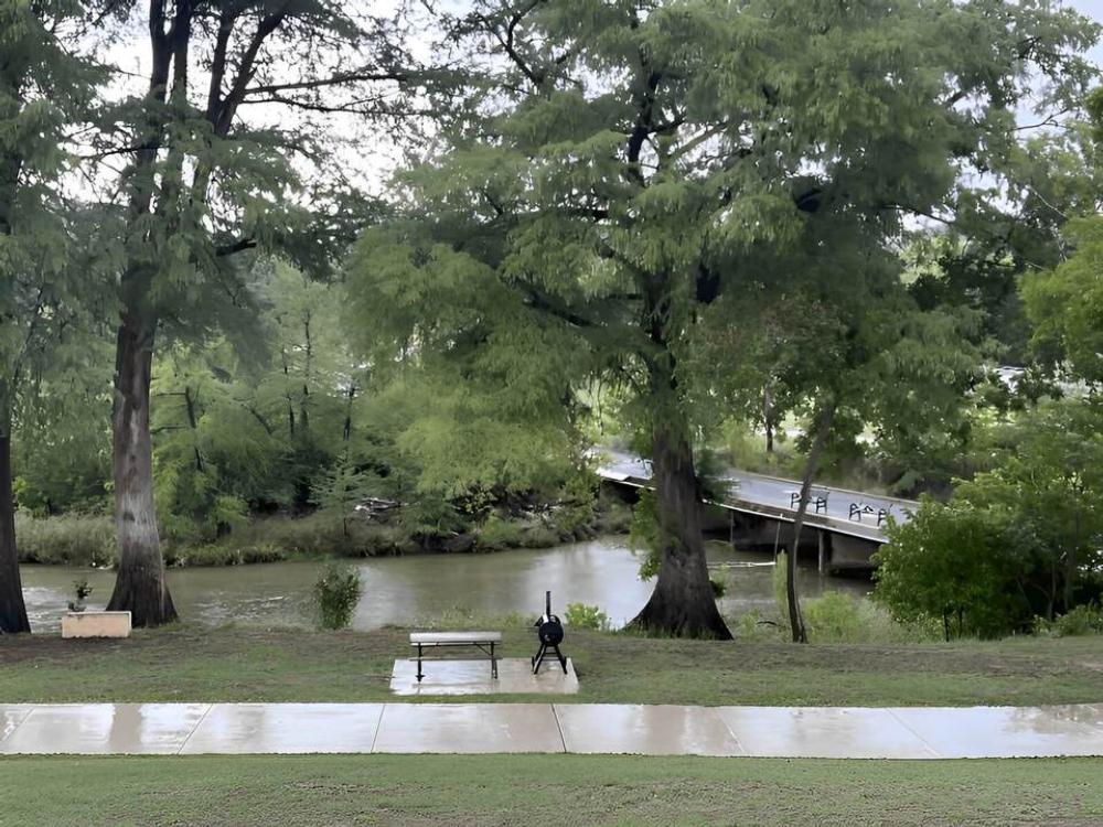 A picnic table and grill by the river at River Trail Cottages & RV Park