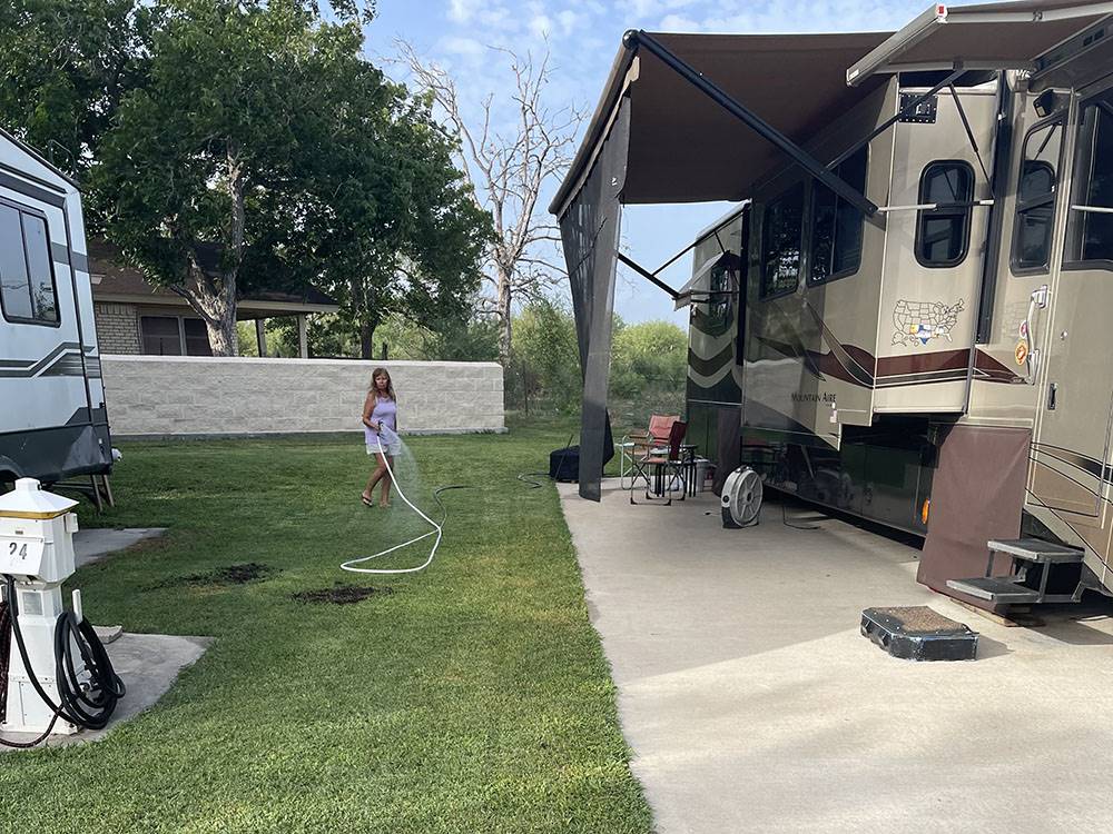 A woman watering her grass at site
