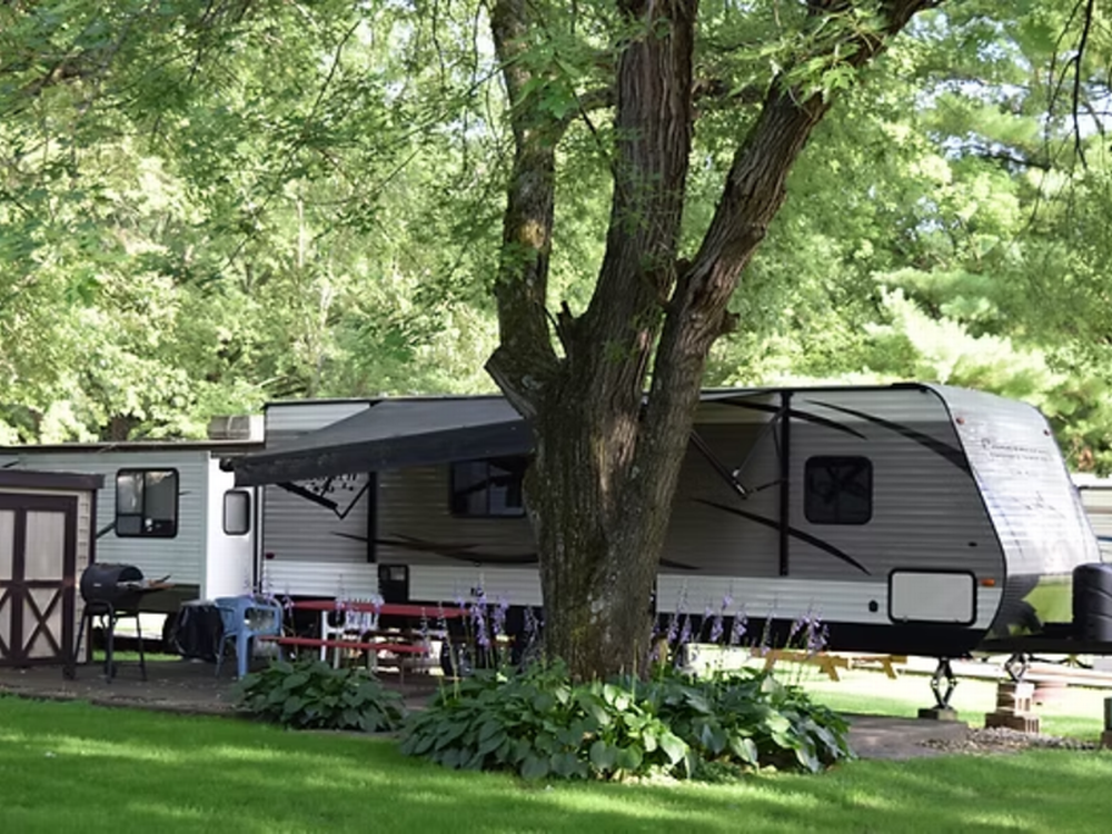 Trailer by a tree at Red Barn Campground & Restaurant