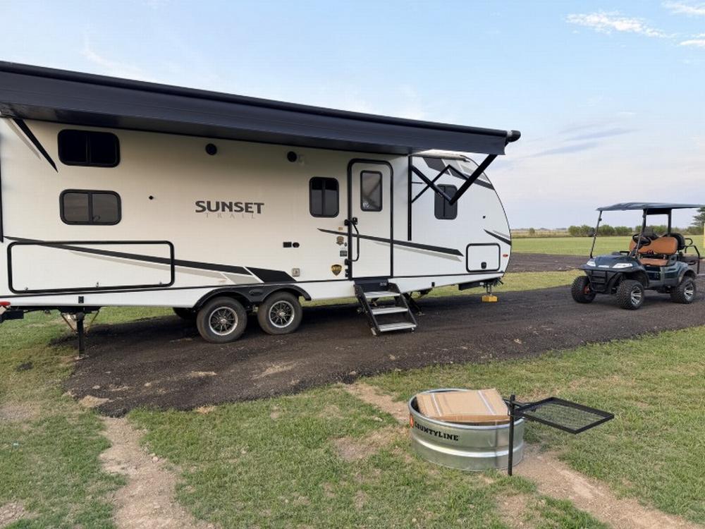 Parked trailer near fire pit at Yoder Outpost RV Campground