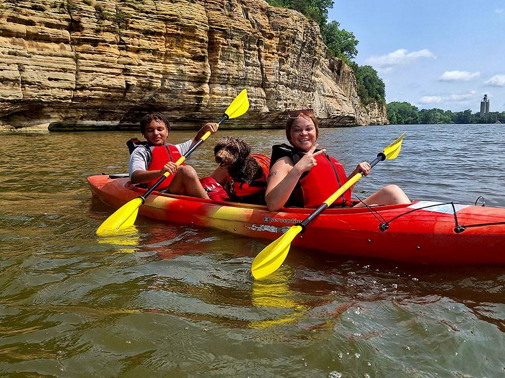 Two people and a dog posing for a photo in a kayak