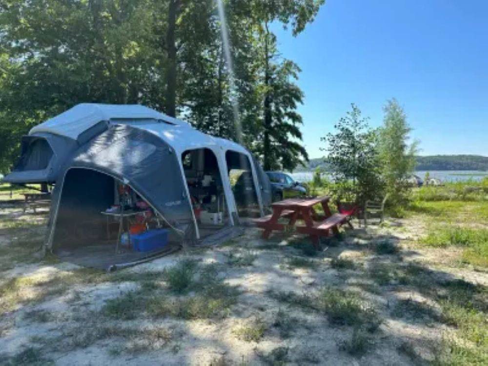 A shaded tent site with a river view