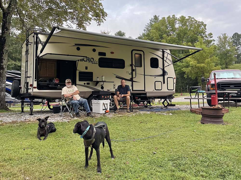 Two men and their dogs at a campsite