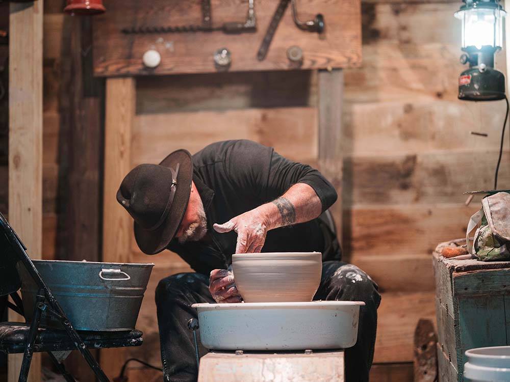 A man making a bowl on a pottery wheel
