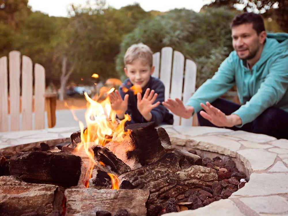 Kid and father around a fire pit