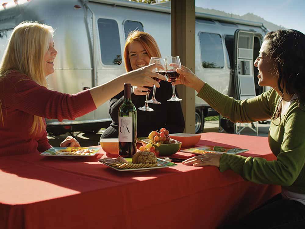 Women enjoying food and drinks outside an Airstream at PECHANGA RV RESORT