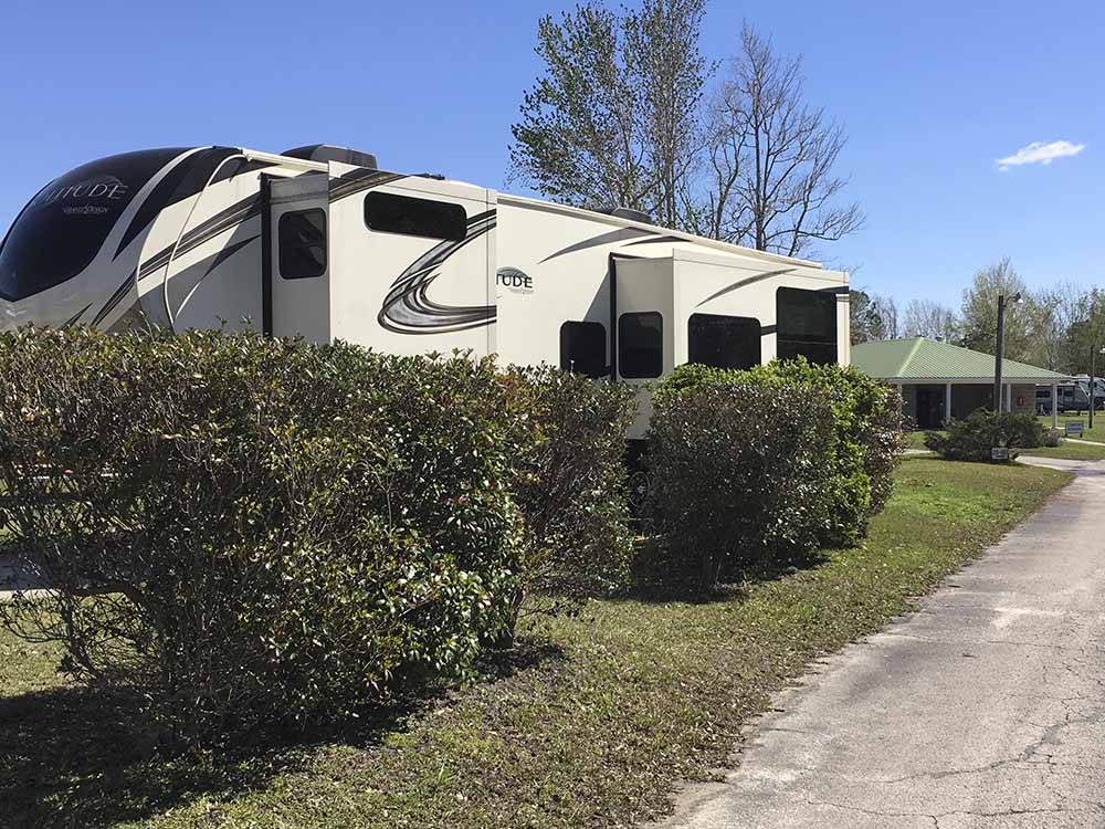 A fifth wheel trailer parked behind some shrubs at CAMPGROUNDS OF THE SOUTH