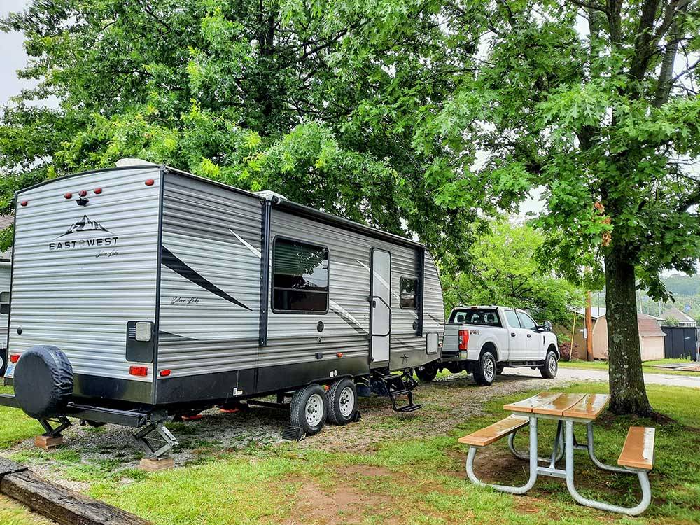 A travel trailer hitched to a white truck in a RV site at WESTGATE RV CAMPGROUND