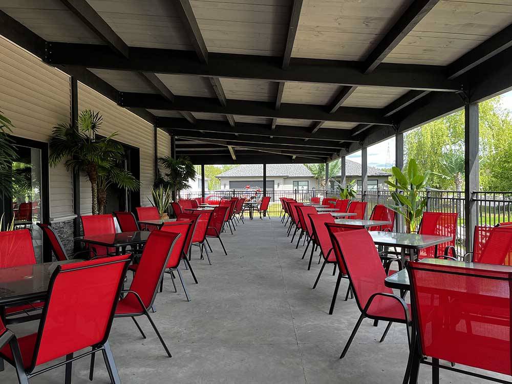 Red chairs and tables under a shady area at CAMPING VALLEE BLEUE RESORT, ENR.199426