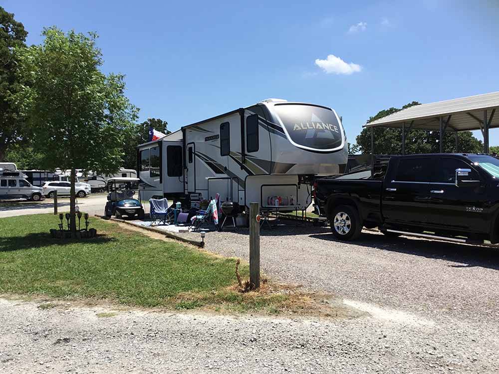 A fifth wheel and truck in a pull thru site at LAZY L RV PARK