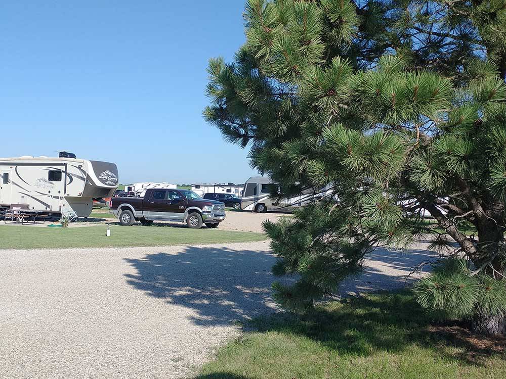 Gravel road and RV sites with RVs and trailers at A PRAIRIE BREEZE RV PARK