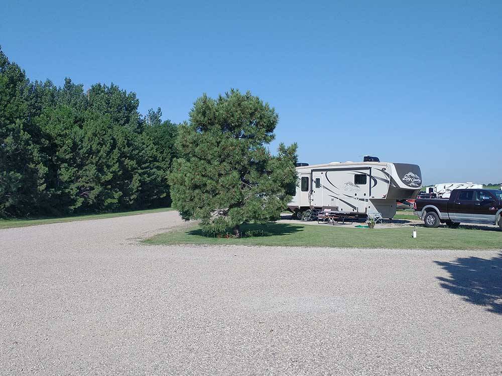 5th wheel parked on site next to a tree at A PRAIRIE BREEZE RV PARK