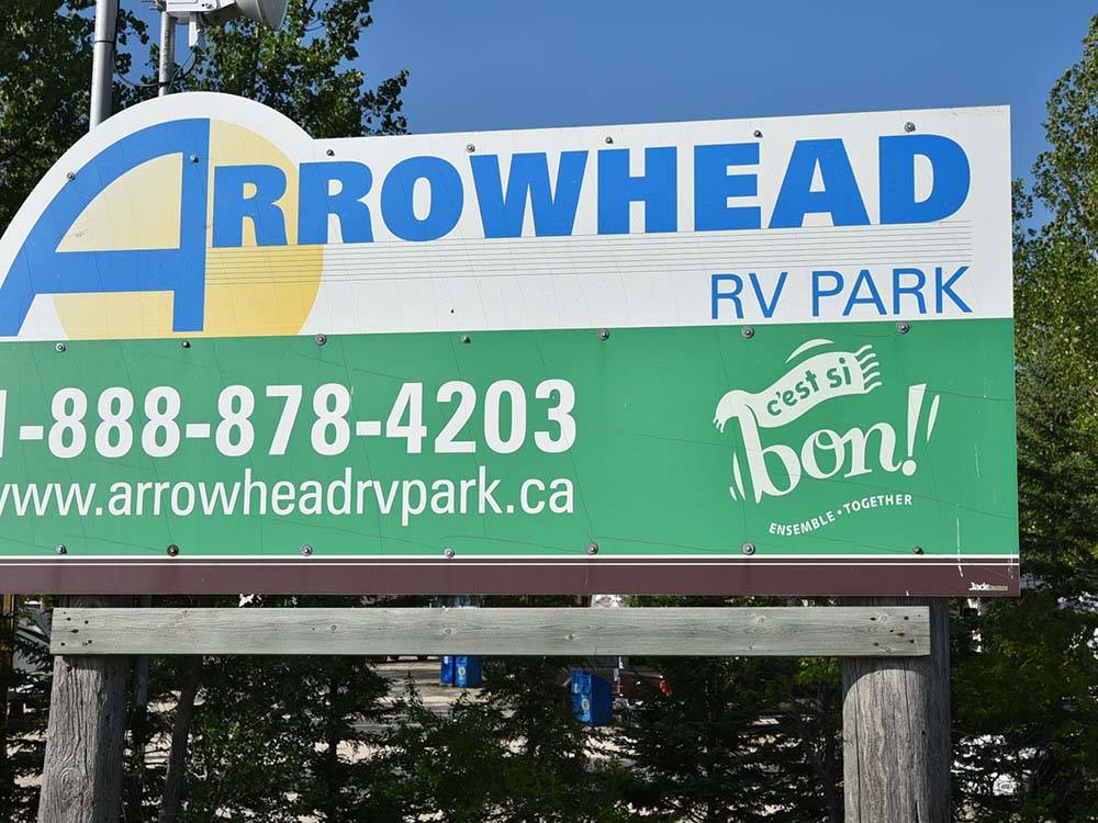 Entrance sign with website and phone number at ARROWHEAD RV PARK