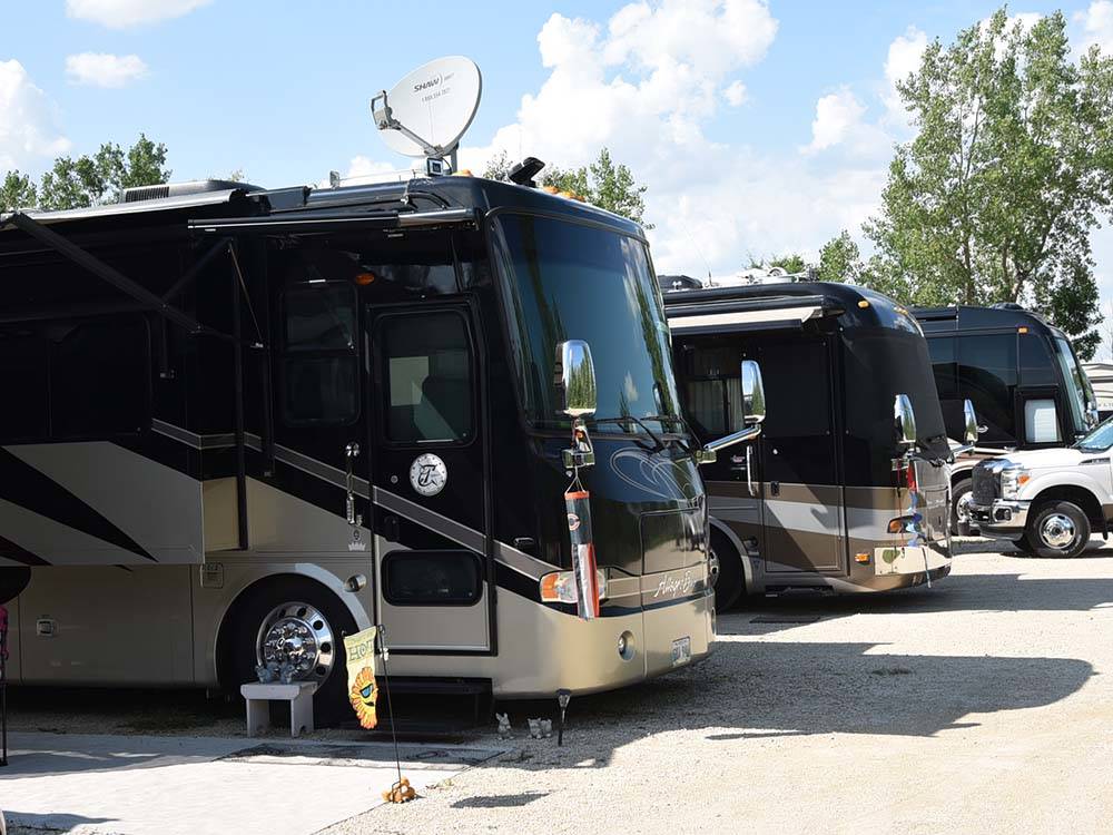 A row of Motorhomes parked in gravel sites at ARROWHEAD RV PARK