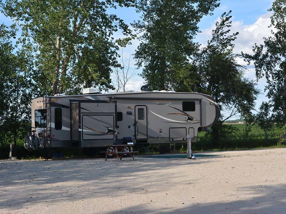A fifth wheel parked next to a picnic bench at ARROWHEAD RV PARK