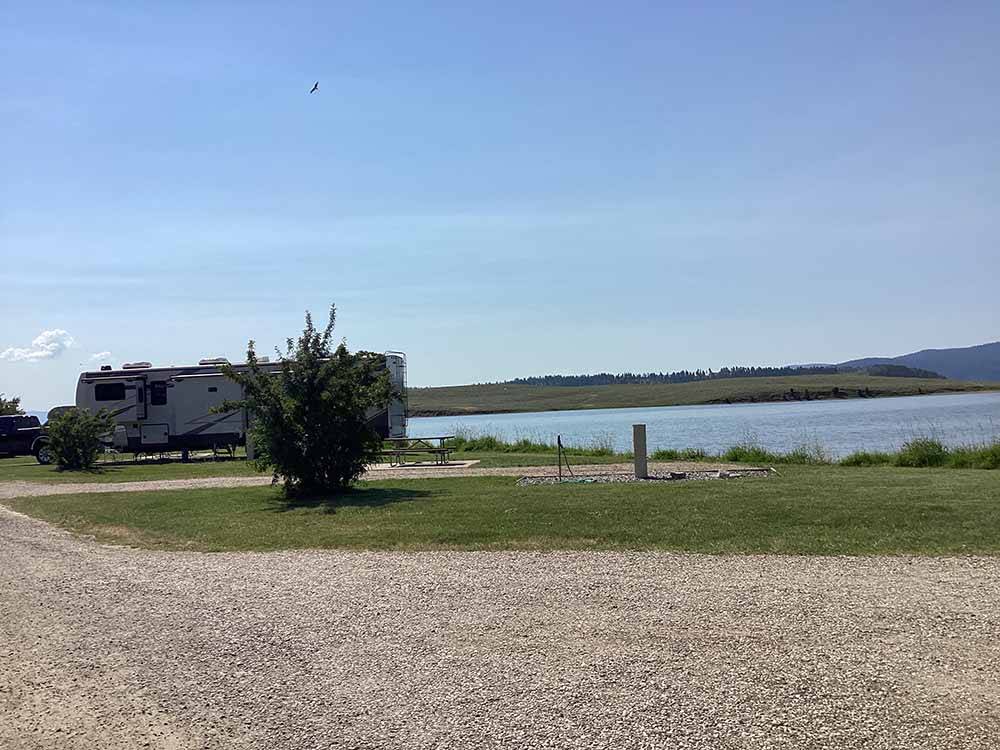 A row of back in gravel RV sites by the water at YELLOWSTONE HOLIDAY RV CAMPGROUND & MARINA