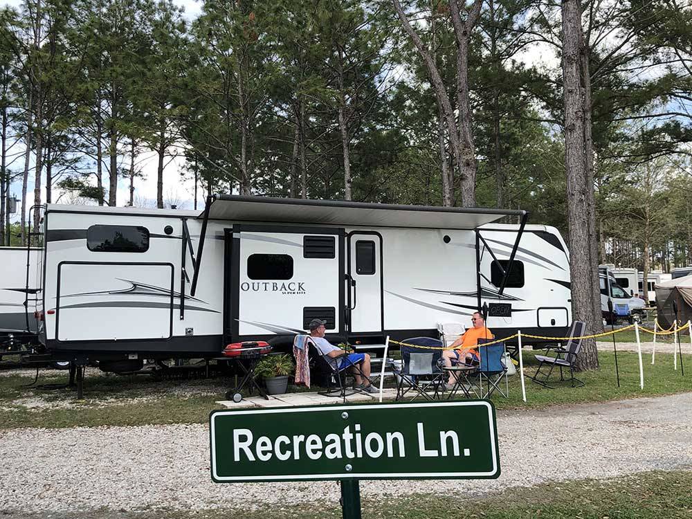 Parked trailer with couple and sign reading Recreation Ln at LAKE CITY RV RESORT