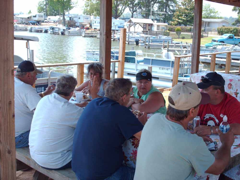 Friends gathered around a table to eat at MOON LANDING RV PARK & MARINA